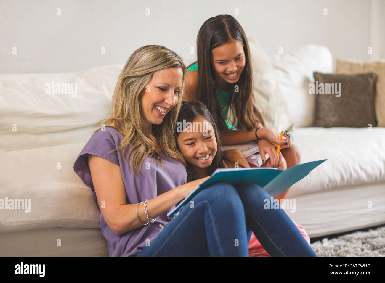 Lettura di madre per le sue figlie e li aiutano con i loro compiti Foto Stock
