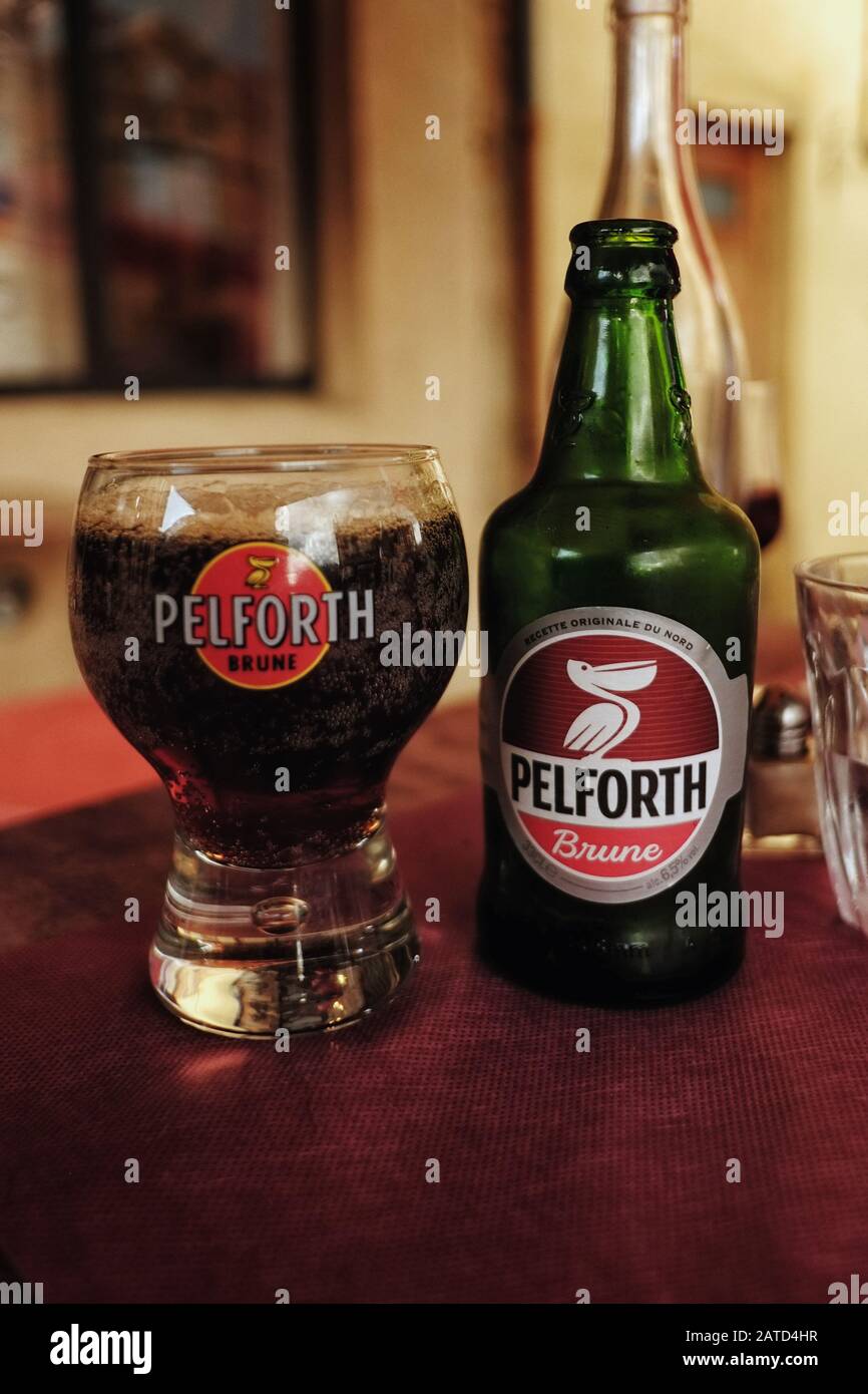 Una bottiglia di birra scura PELFORTH Brune con un bicchiere rotondo abbinato per la birra francese del nord fotografata su un tavolo da caffè della contea pomeriggio Foto Stock