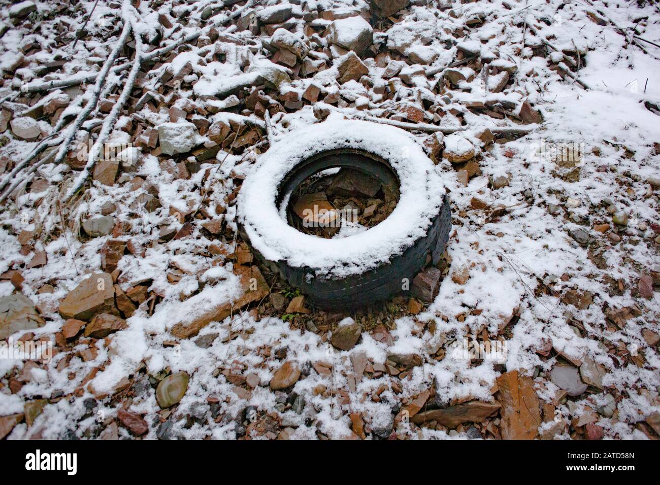 Un vecchio pneumatico innevato, sul lato di una collina in un sito di scarico illegale dal ritorno nella 1950s, e 1960s, a sud-est di Troy, Montana. Foto Stock