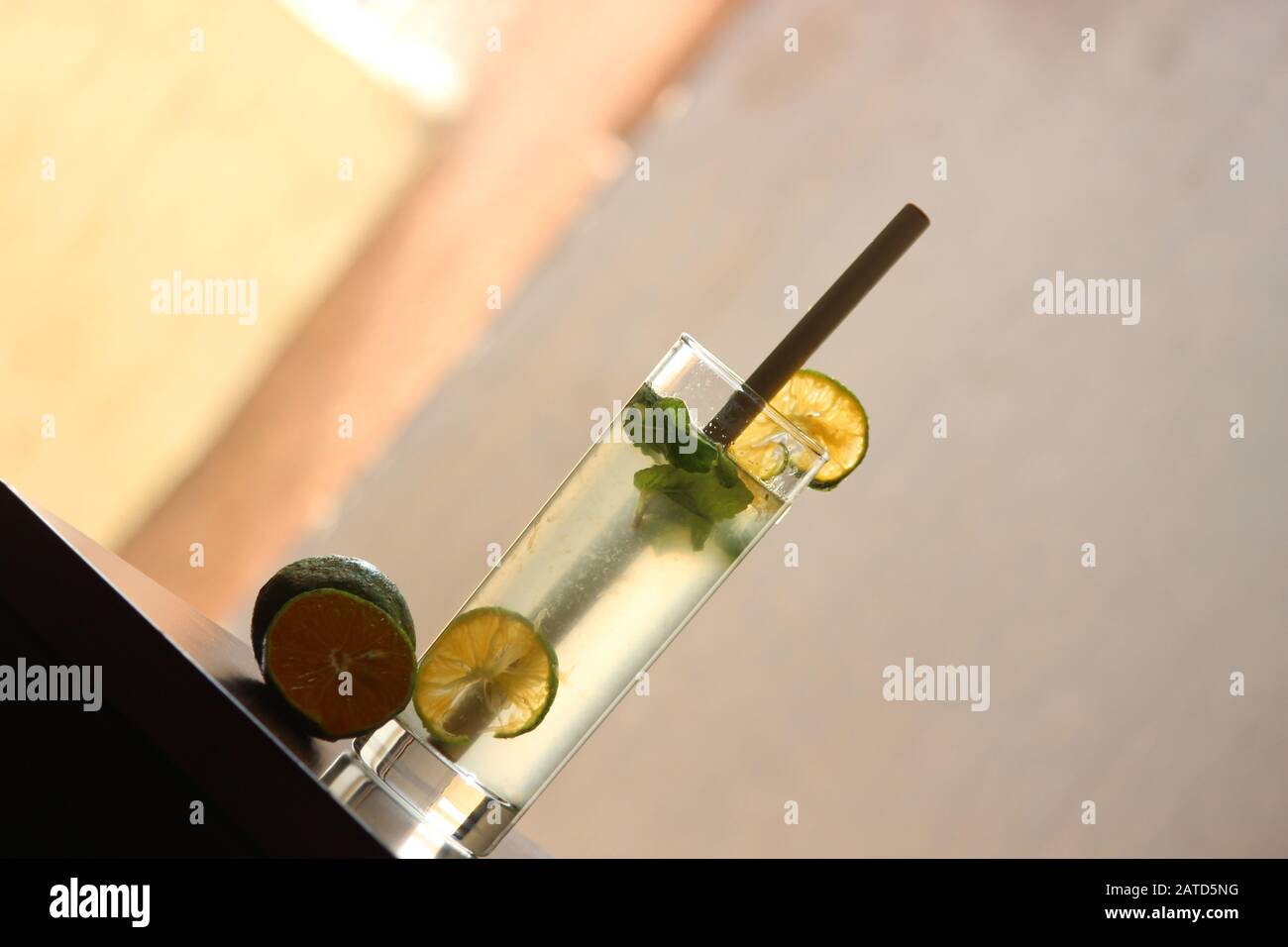 Limonata soda in Tall vetro con cannuccia di bambù con foglie di menta e limoni freschi tagliati sullo sfondo Foto Stock