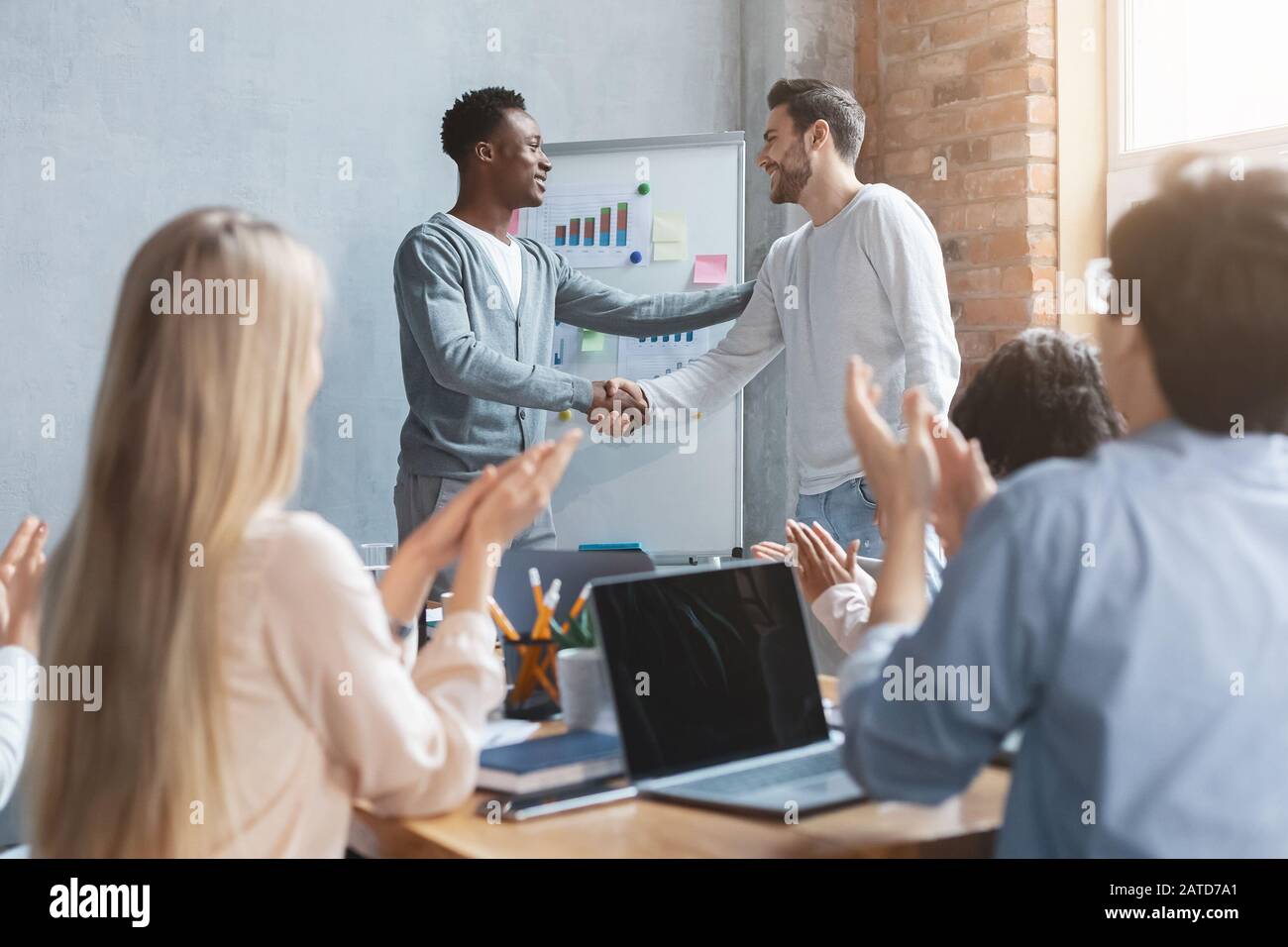 Il responsabile africano positivo che si scuote mano al dipendente caucasico Foto Stock