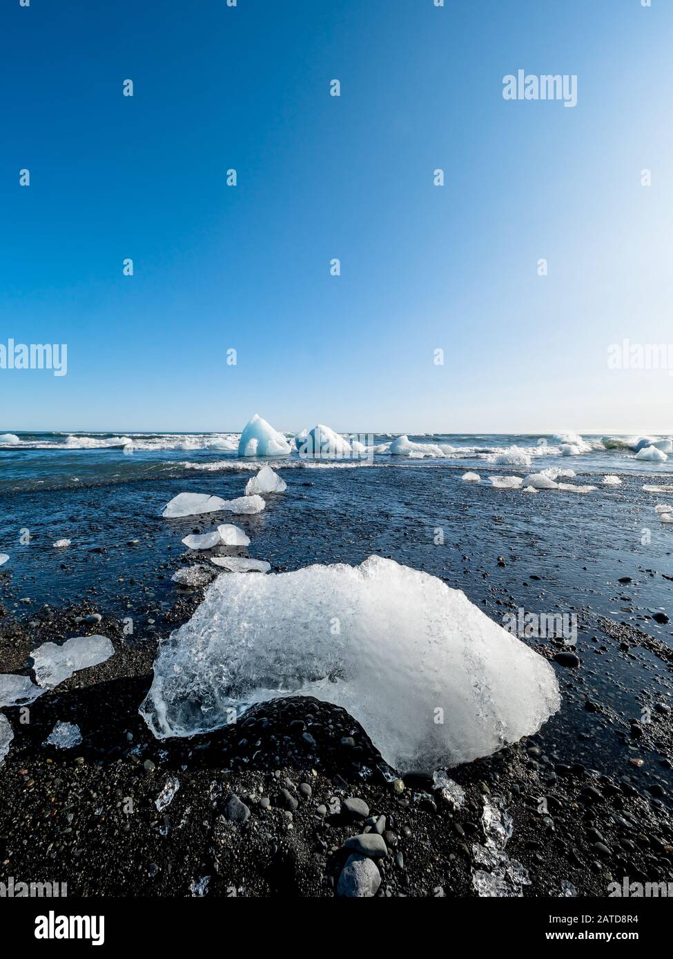 Grande ghiaccio su sabbia nera, parte di un iceberg dal ghiacciaio di Jokulsarlon nella spiaggia di Diamond, uno dei luoghi più turistici in Islanda. Foto Stock