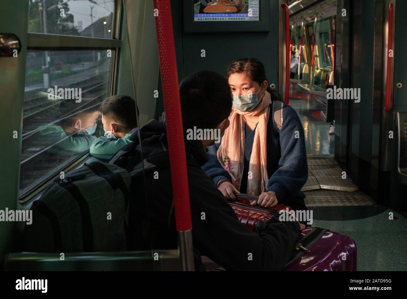 Una famiglia all'interno di un treno MTR in direzione di lo Wu al confine con Shenzhen indossare maschere chirurgiche a Hong Kong. L'Organizzazione Mondiale della Sanità ha chiamato un'emergenza sanitaria globale, invertendo la decisione precedente su focolaio di coronavirus. Finora ci sono 13 casi confermati di coronavirus a Hong Kong, mentre il totale dei casi confermati è salito a 14.549 e il numero dei decessi è salito a 305. Foto Stock