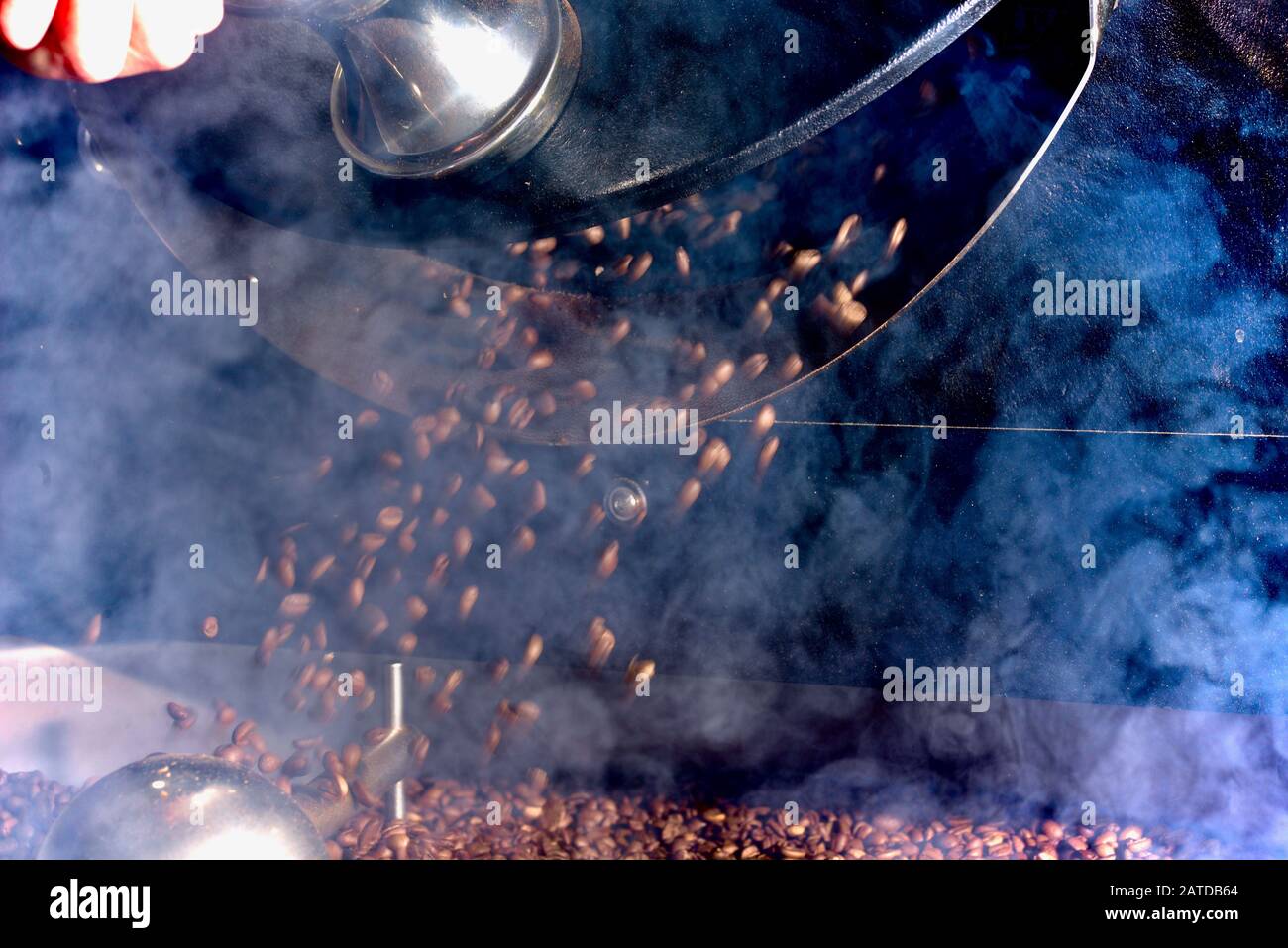 I chicchi di caffè appena tostati vengono versati dalla torrefazione Foto Stock