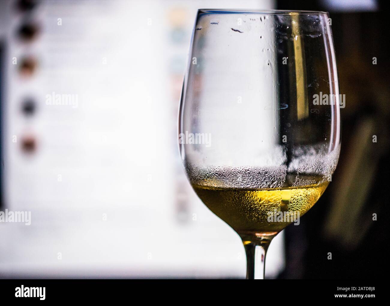 Un bicchiere di vino bianco freddo, con schermo per computer sullo sfondo Foto Stock