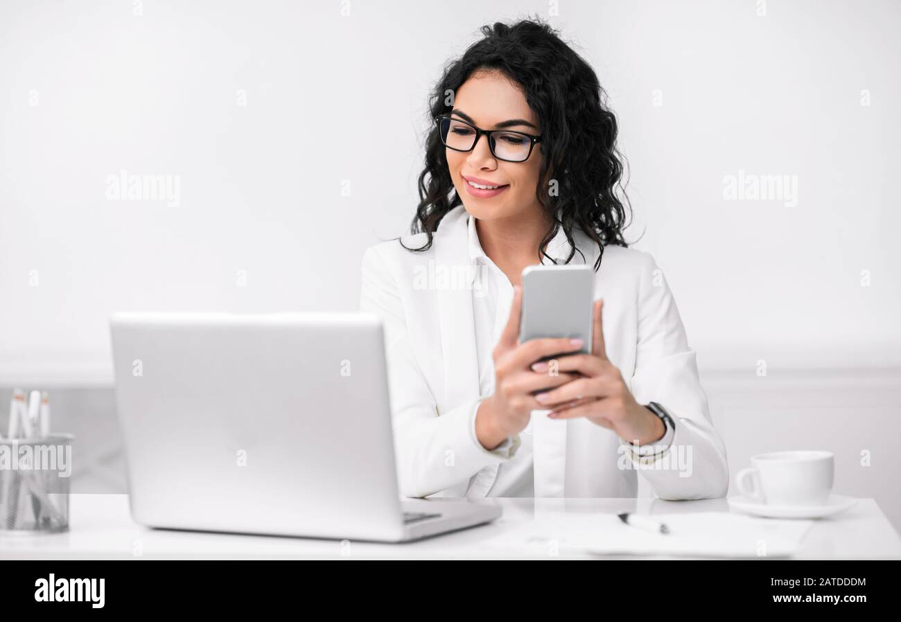 Ritratto di ragazza ispanica occupata con cellulare e computer Foto Stock