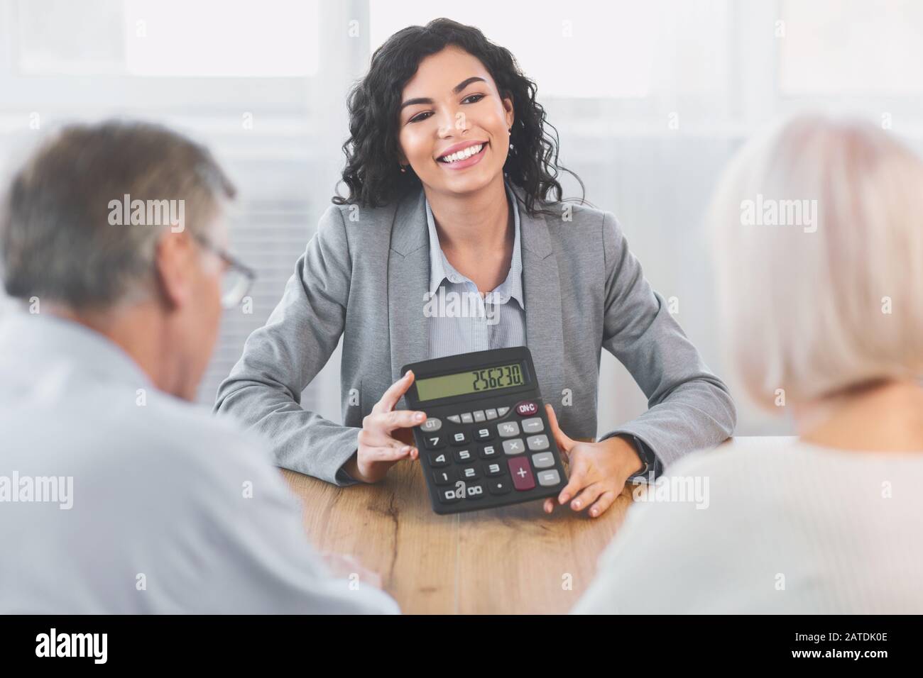 Consulente finanziario messicano che mostra calcolatrice per coppia matura Foto Stock