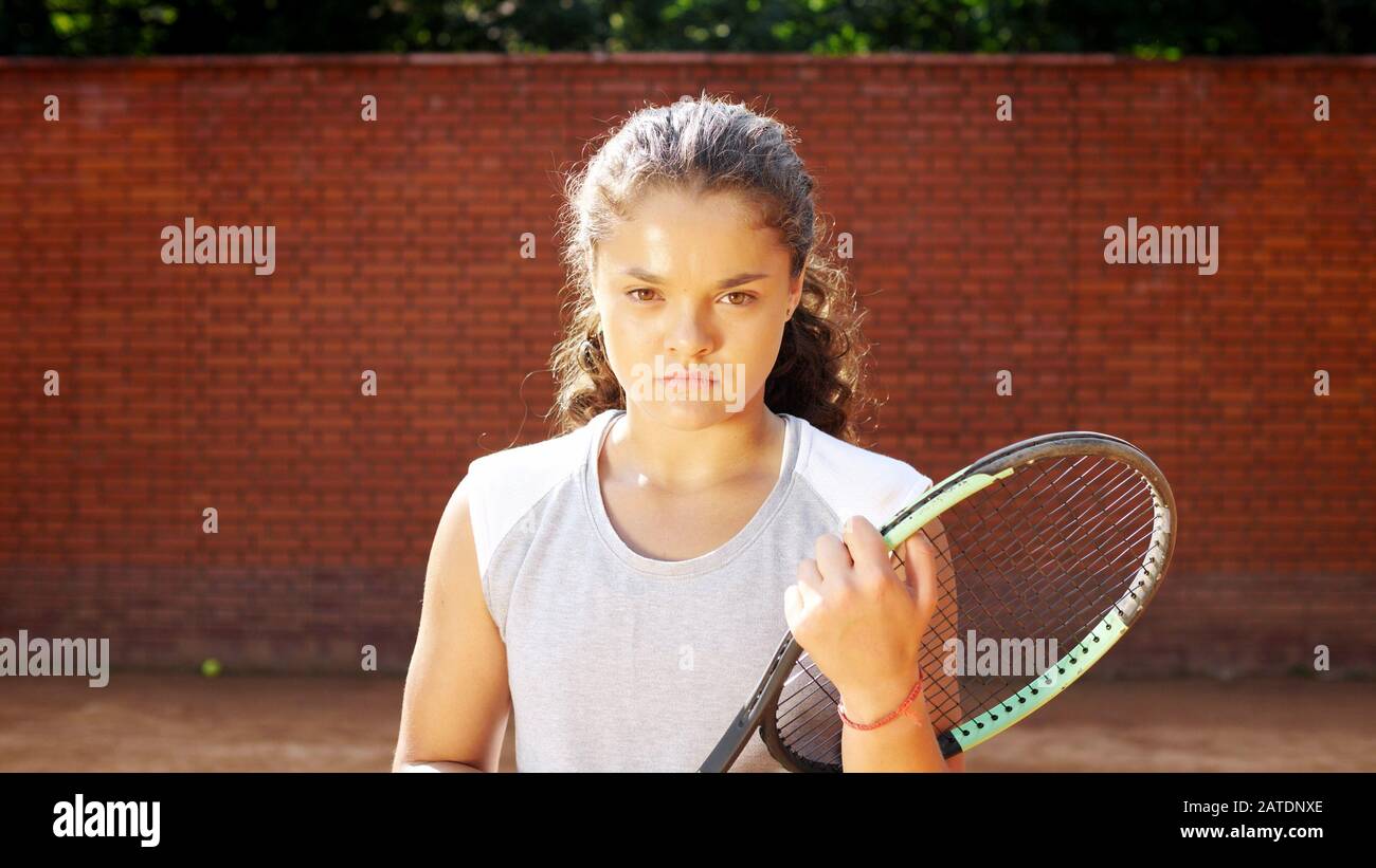 Ritratto di bella giovane tennis playgirl andare con racket sul campo da tennis arancione argilla Foto Stock
