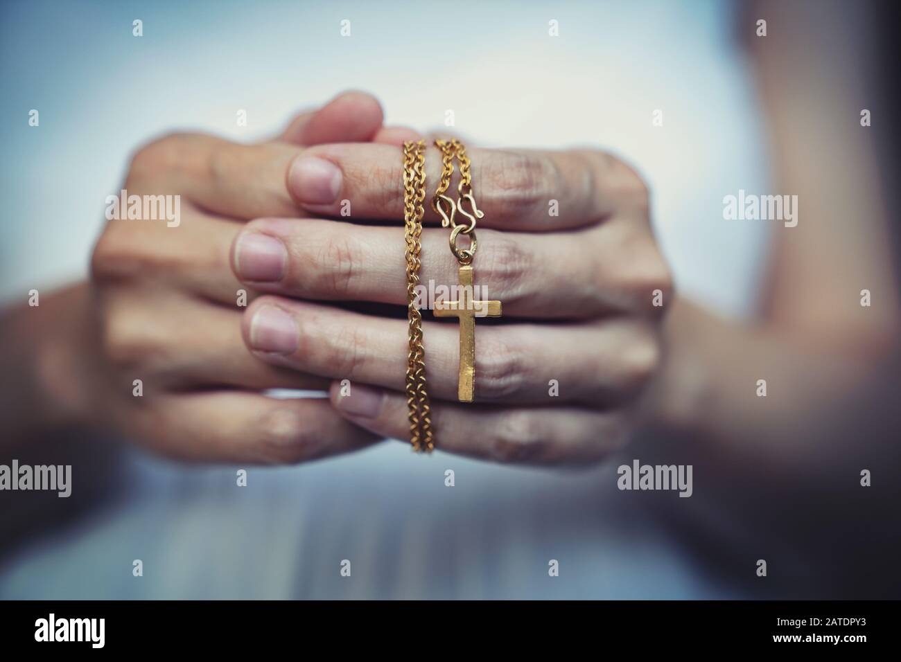 Mani di donna che pregano tenendo un rosario di perle con Gesù Cristo nella croce o Crocifisso su sfondo nero. Foto Stock