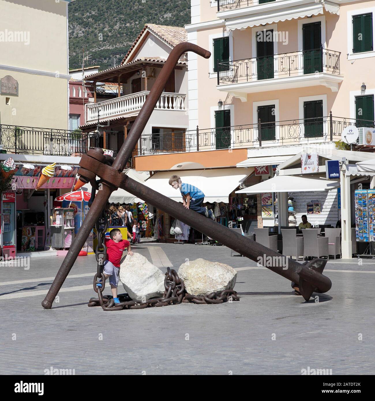 I ragazzi di tow tow giocano su un'ancora disusata sul lungomare della città di Parga nella Grecia nord-occidentale. Foto Stock