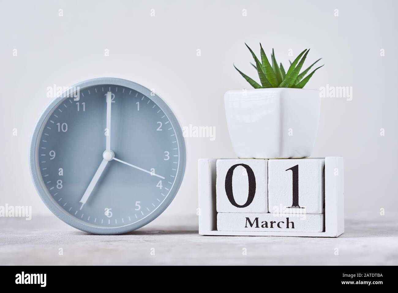 Sveglia con blocco di legno calendario data 1st marzo e pianta sul tavolo Foto Stock