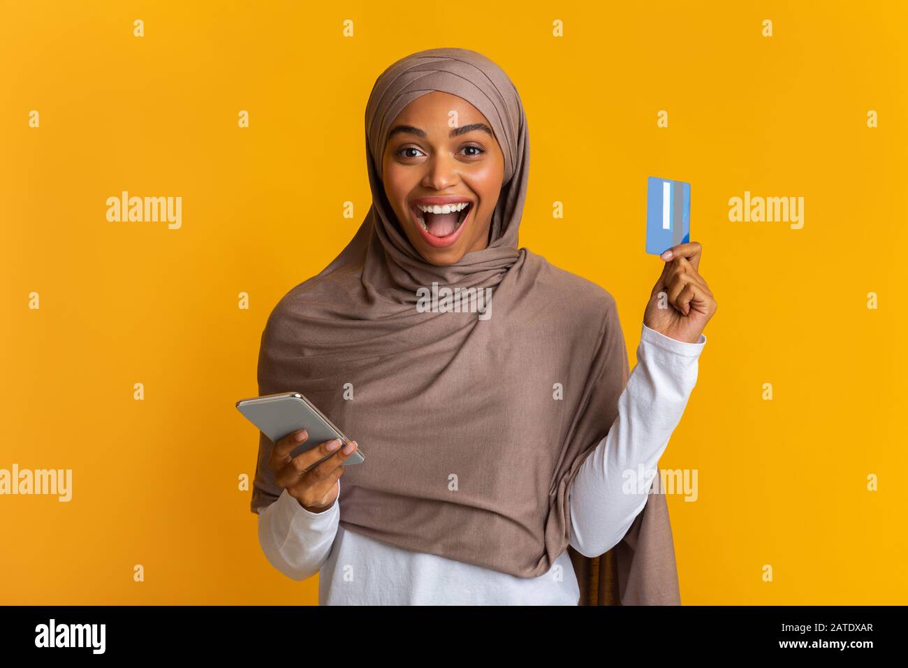 Ragazza Musulmana Nera Con Gioia In Hijab Holding Carta Di Credito E Smartphone Foto Stock