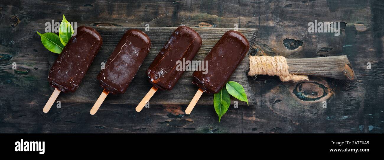 Gelato al cioccolato su un bastone. Su sfondo nero. Vista dall'alto. Spazio libero di copia. Foto Stock