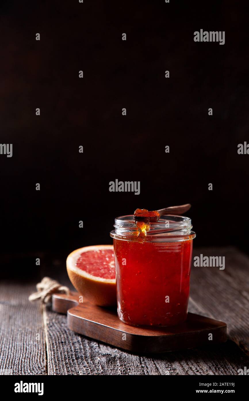 vasetto con marmellata di pompelmo su un vecchio sfondo di legno in stile scuro. Foto Stock