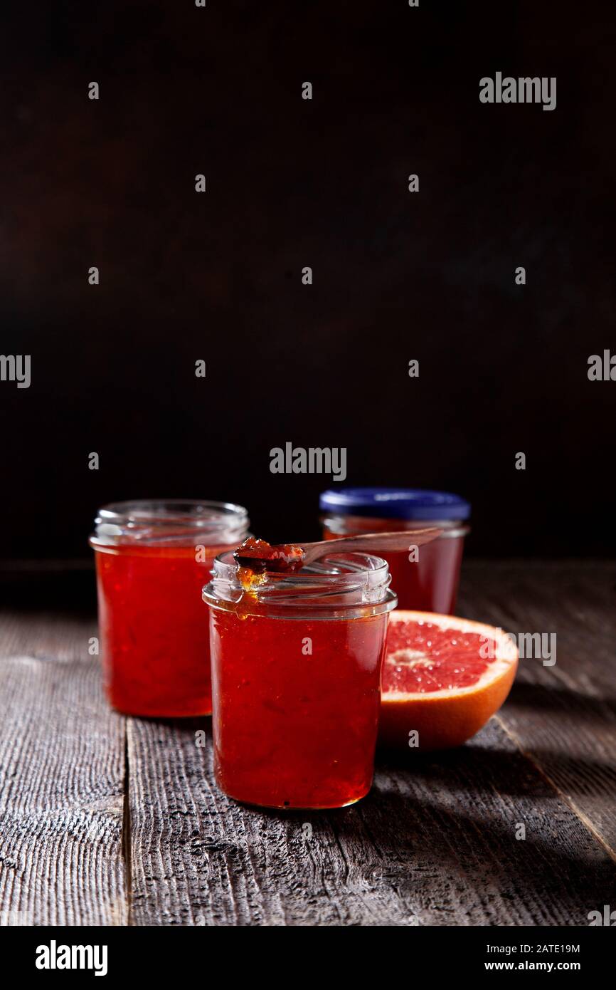 vasetto con marmellata di pompelmo su un vecchio sfondo di legno in stile scuro. Foto Stock