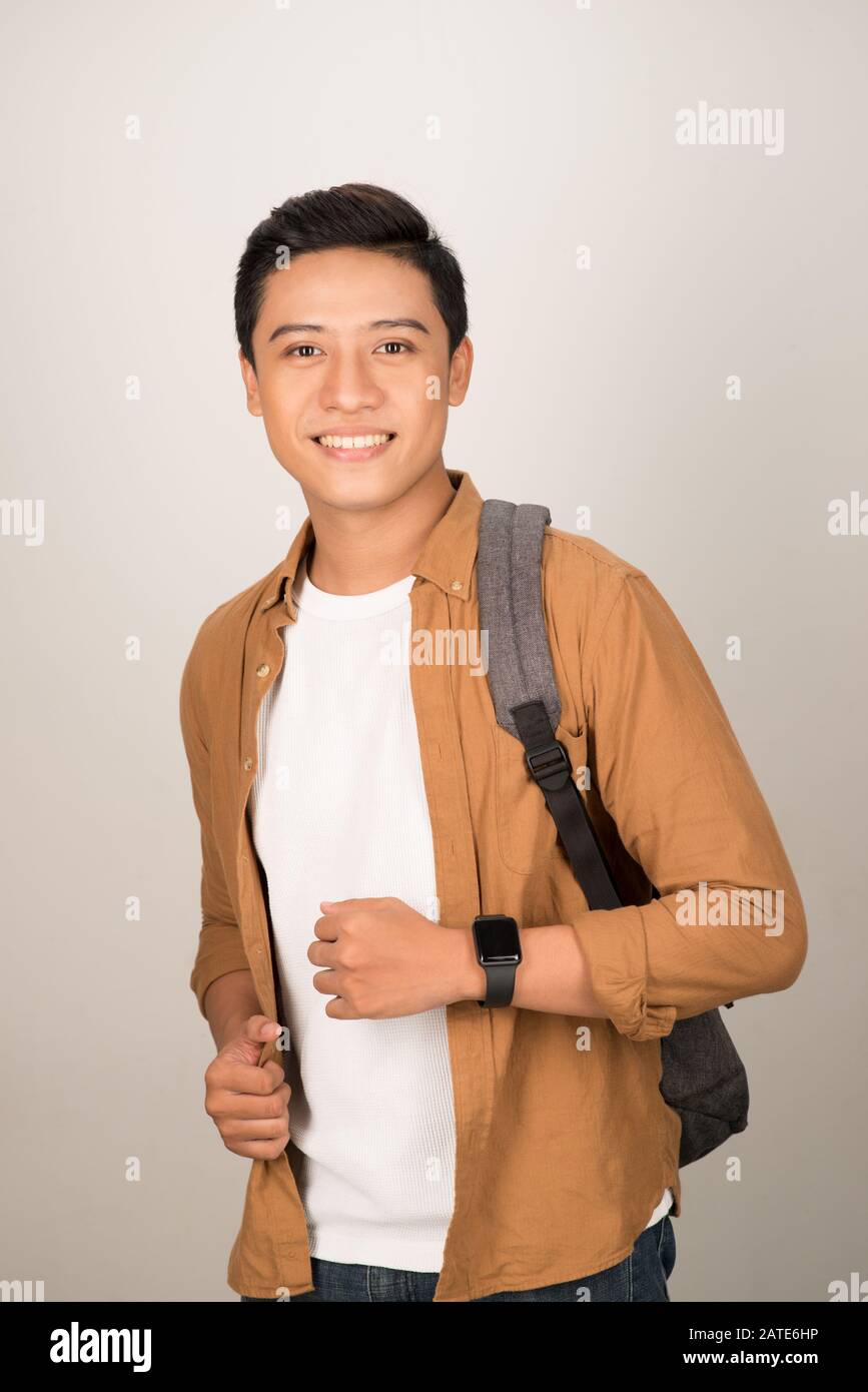 Una vista laterale verticale di un sorridente studente portando il suo zaino, isolato su uno sfondo bianco Foto Stock