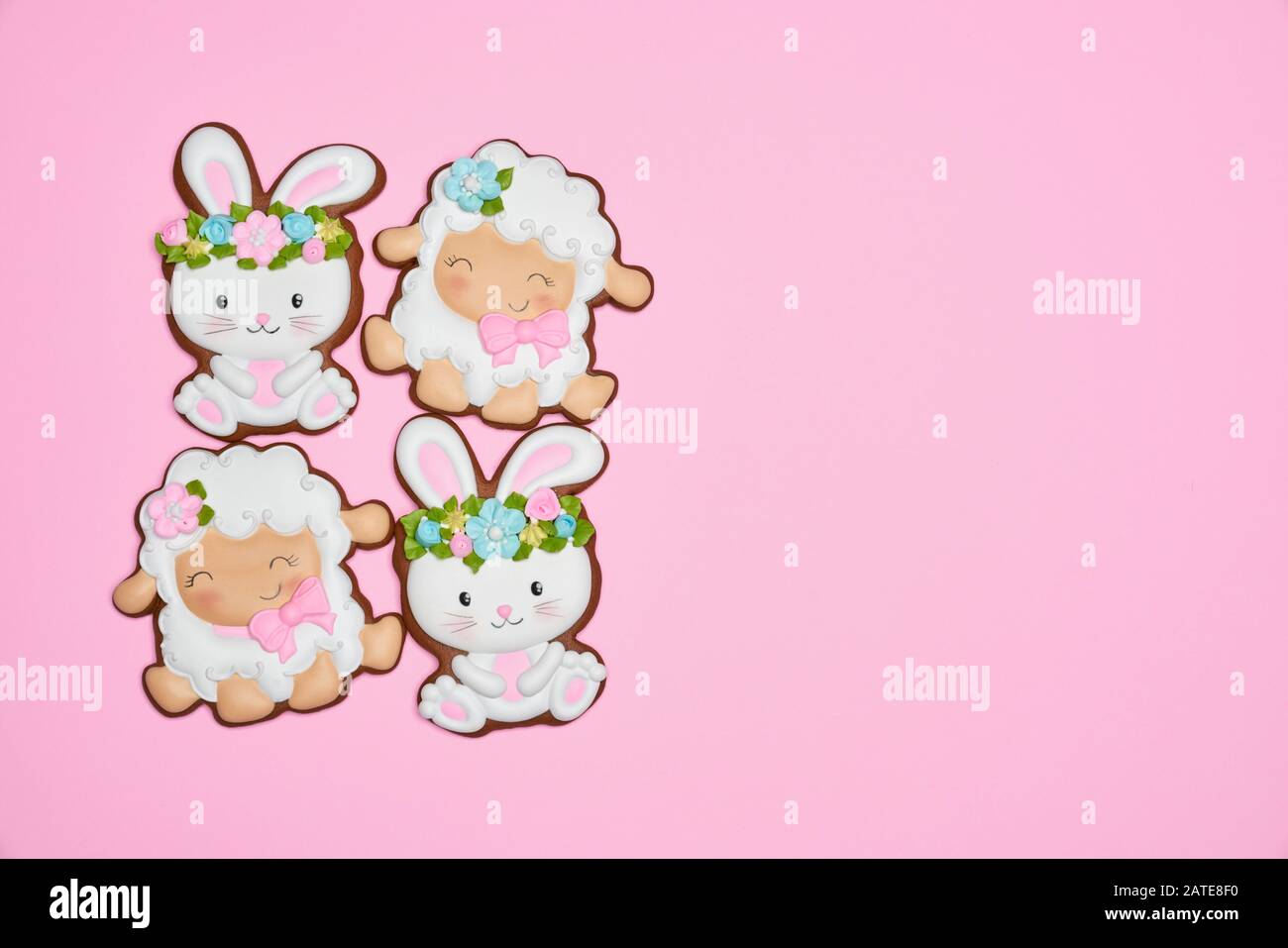 Vista dall'alto di biscotti smaltati isolati su sfondo rosa. Biscotti allo zenzero di Pasqua in forma di due coniglietti in wreaths e due pecore che fanno piazza. Concetto di vacanze di primavera e pasqua. Foto Stock