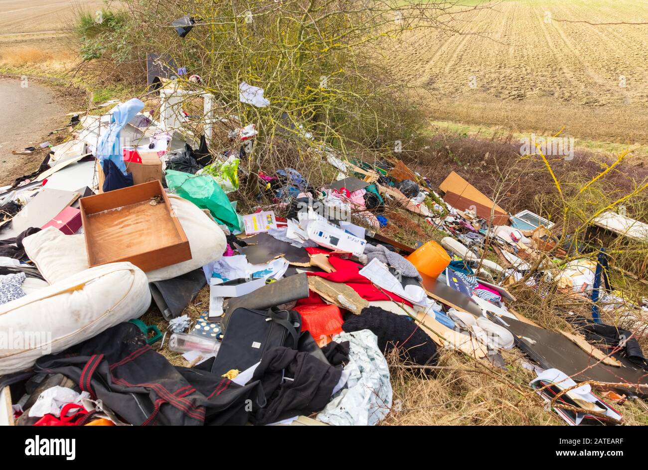 Vola giù per una tranquilla strada di campagna. La quantità estrema di rifiuti domestici, scaricati illegalmente in campagna aperta, provoca uno spaventoso blot sulla terra Foto Stock