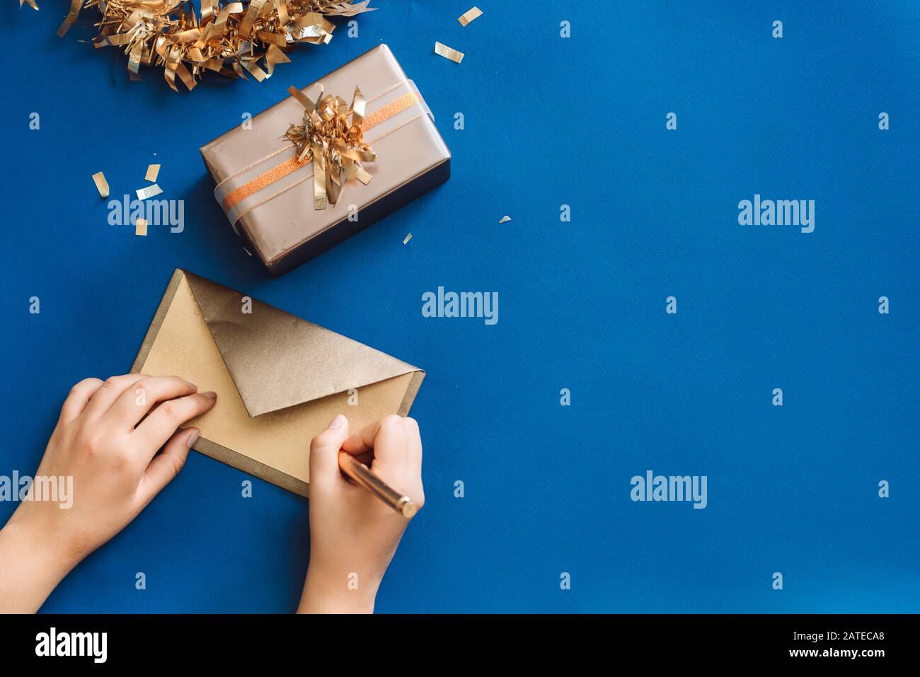 La scrittura di auguri di Natale con gold box e la corona di fiori su sfondo blu Foto Stock
