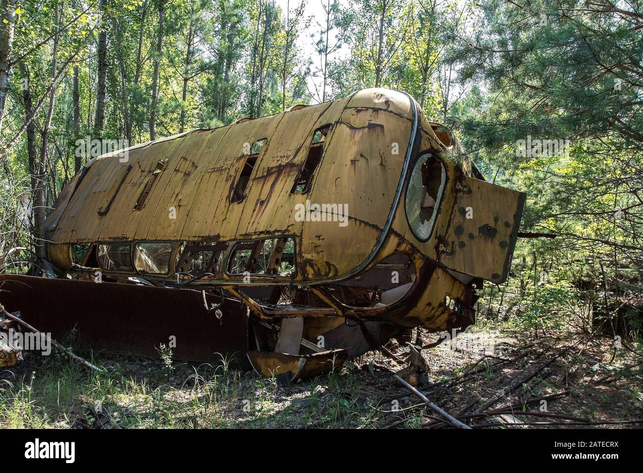 Abbandonato e rusty bus in un campo in una giornata soleggiata con cielo blu e nuvole nella centrale nucleare di Cernobyl la zona di alienazione Foto Stock