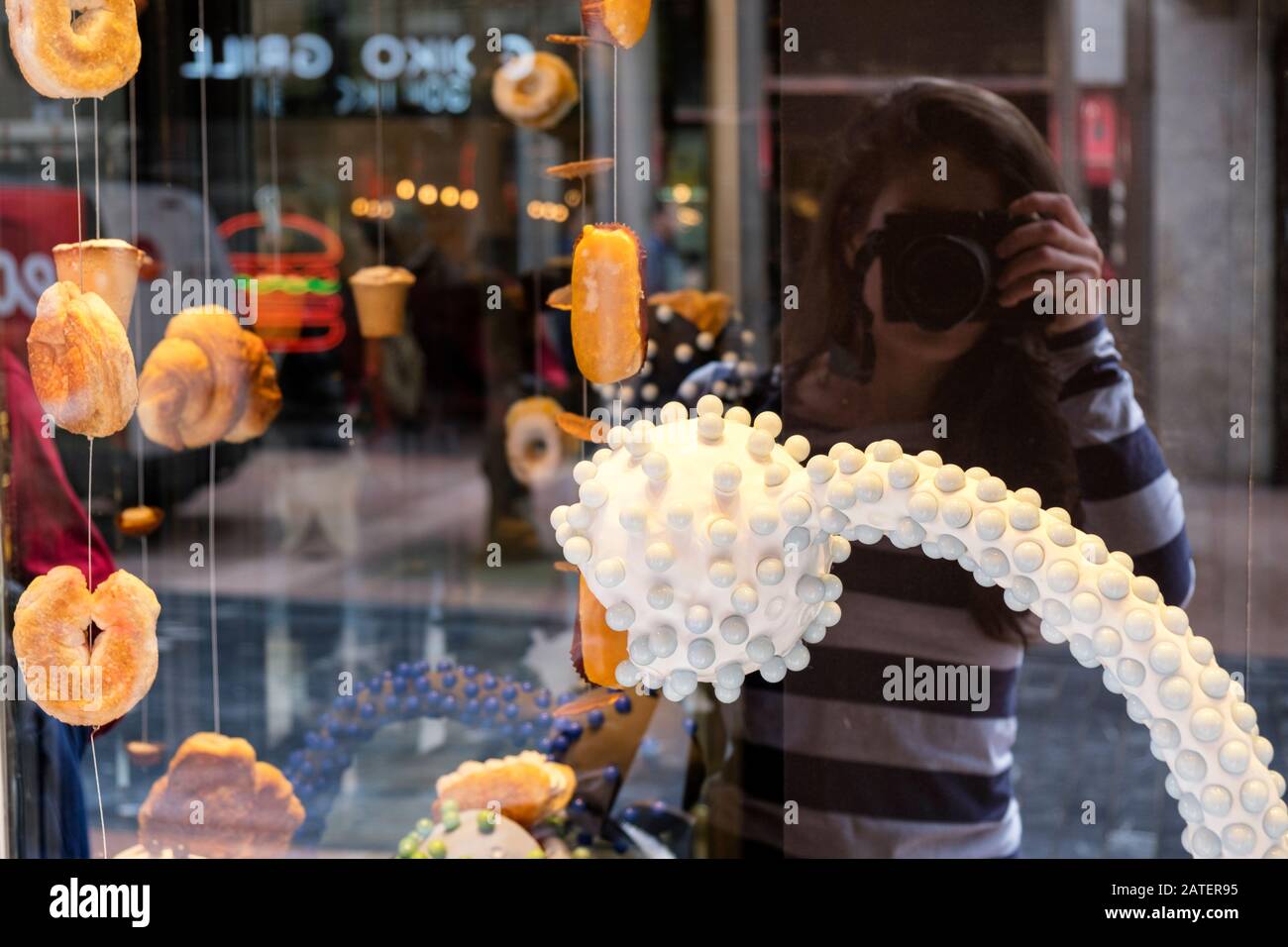 Fotografo femminile che fa un selfie riflesso nella vetrina dei prodotti tradizionali di Rialto (Oviedo, Asturias, Spagna) Foto Stock