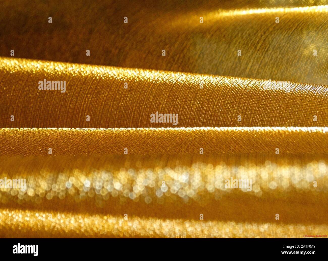 Struttura completa di tessuto dorato piegato come onde d'oro bokeh brillante Foto Stock