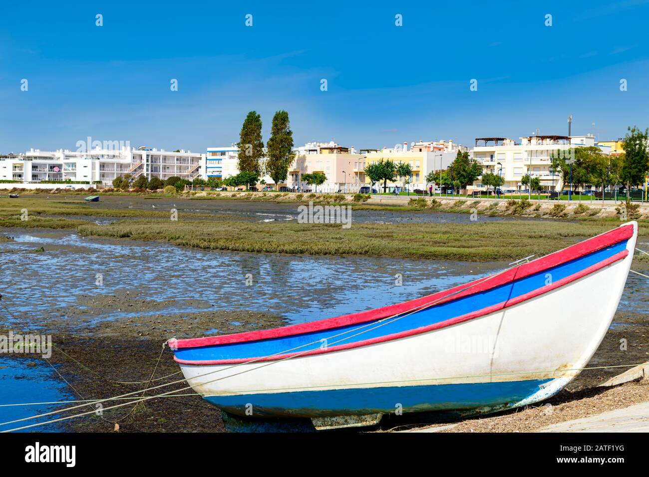 Barca sulla riva del parco nazionale di Ria Formosa con Fuseta East Algarve sullo sfondo. Fuseta, Algarve, Portogallo. Foto Stock