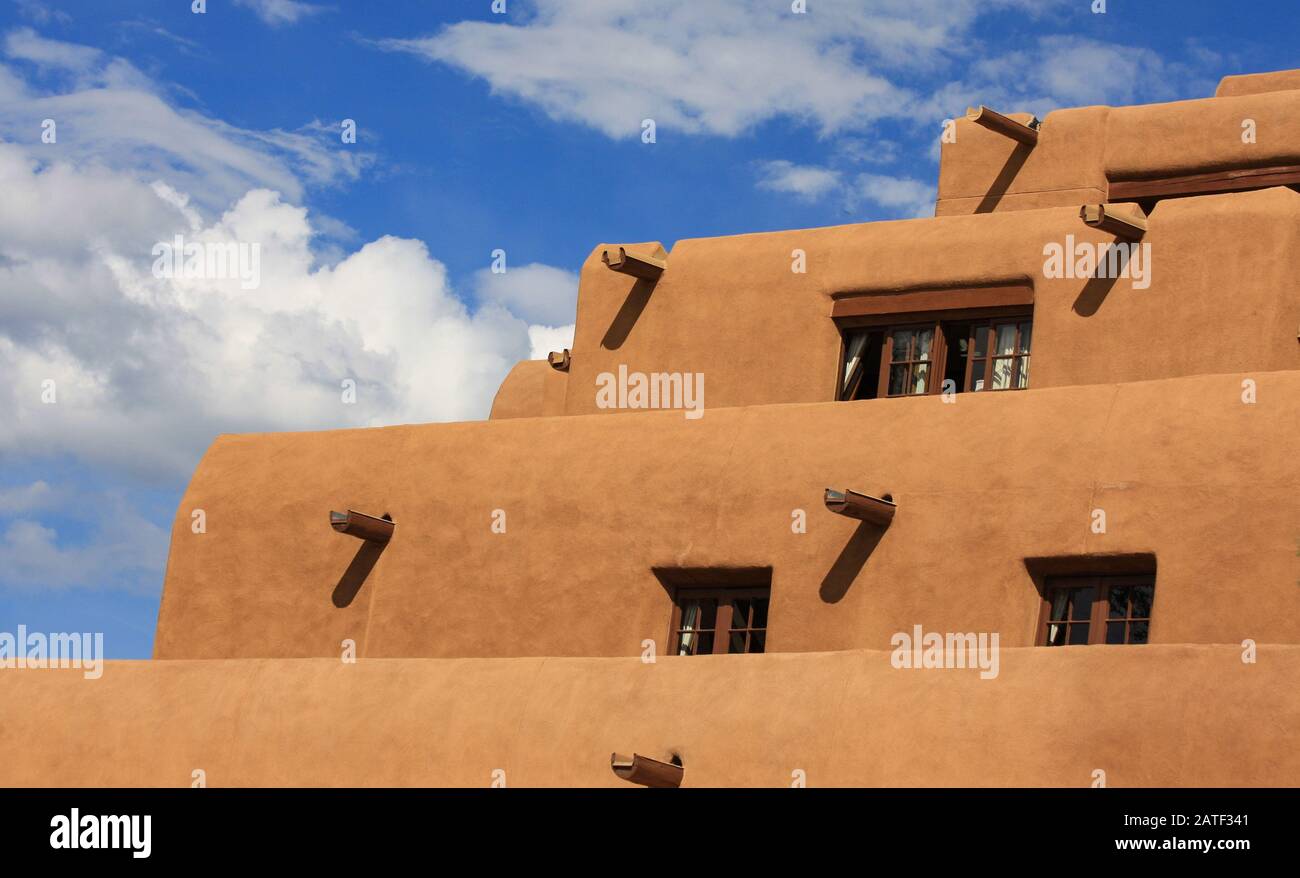 Edificio a gradini in stucco Pueblo adobe. Architettura in gesso di adobe con cielo blu che mostra vigas di legno Foto Stock