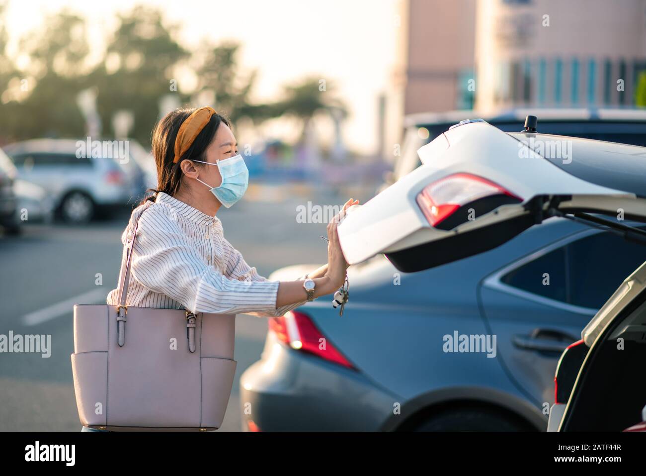 Ragazza asiatica che indossa maschera facciale in un parcheggio all'aperto Foto Stock