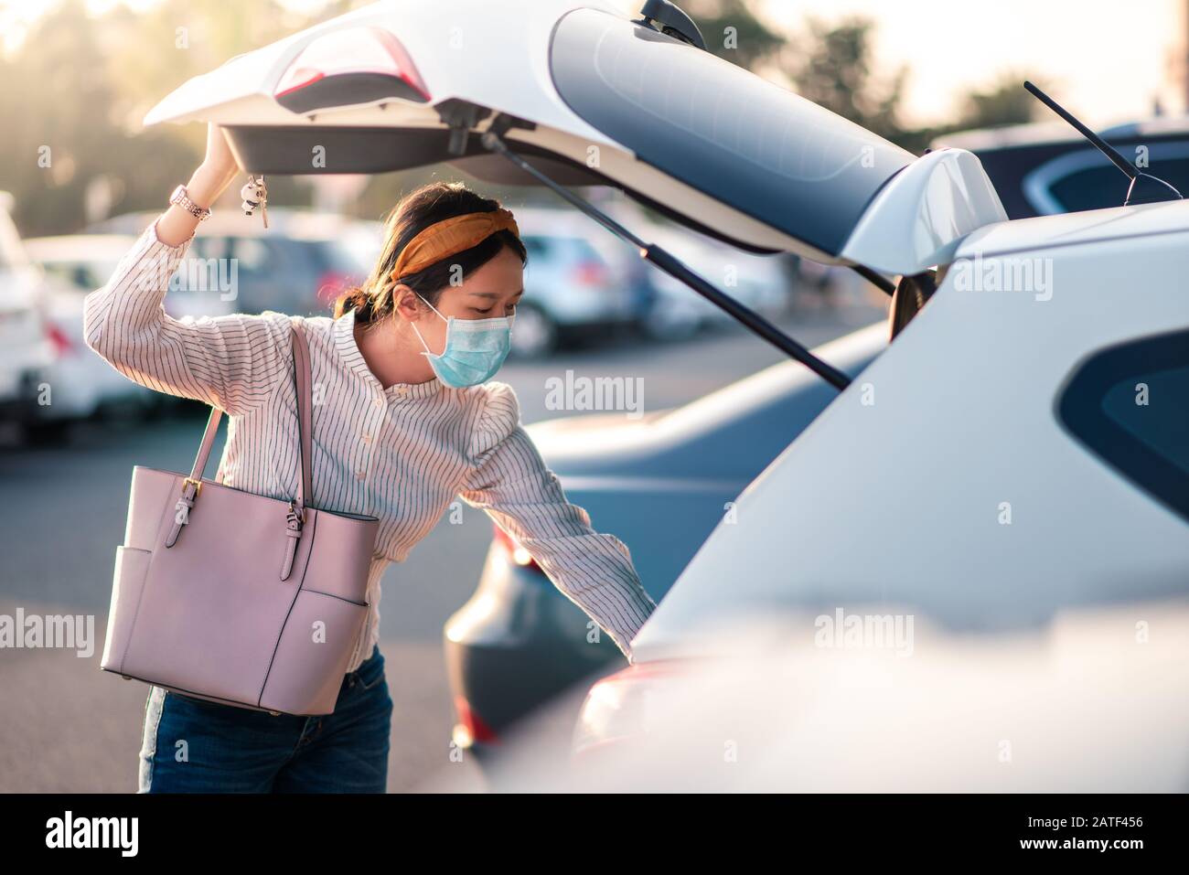 Ragazza asiatica che indossa maschera facciale in un parcheggio all'aperto Foto Stock