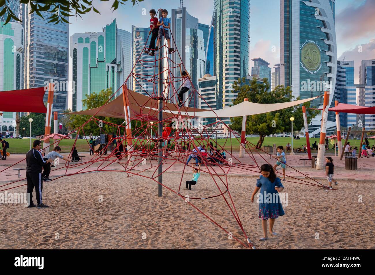 Sheraton Park a Doha Qatar vista diurna con bambini che giocano nel parco giochi per bambini e skyline con nuvole nel cielo in background Foto Stock