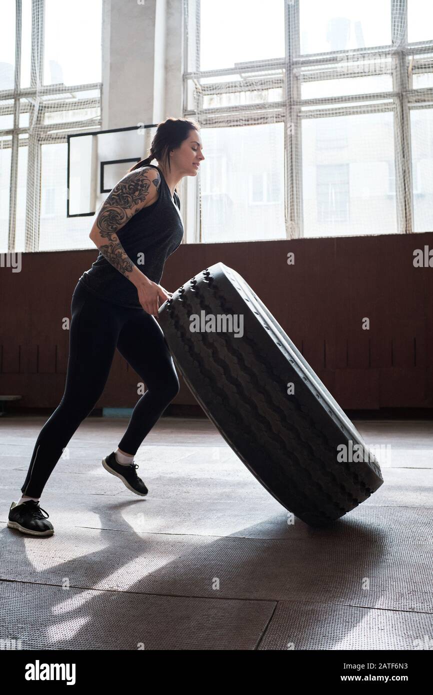 donna sportiva tatuata in black activewear building muscoli da flirt pneumatico Foto Stock