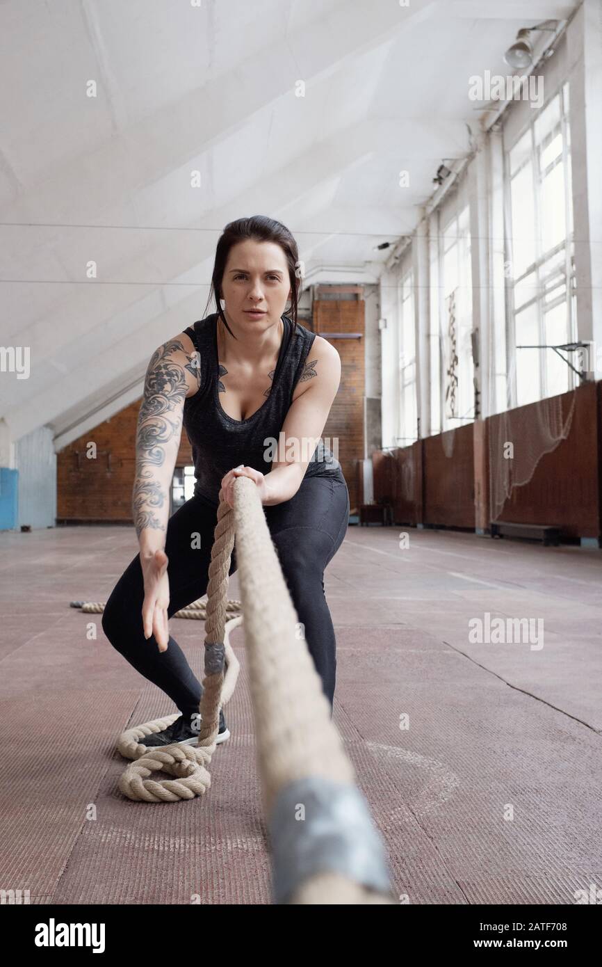 Giovane atleta caucasico attraente femmina con tatuaggi tirare le corde di battaglia Foto Stock