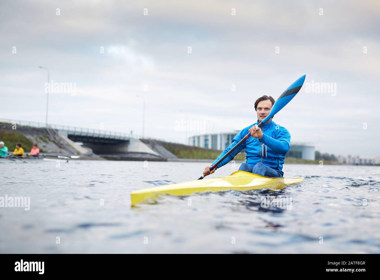 Sportivo caucasico concentrato che pagaia lungo il canale Foto Stock