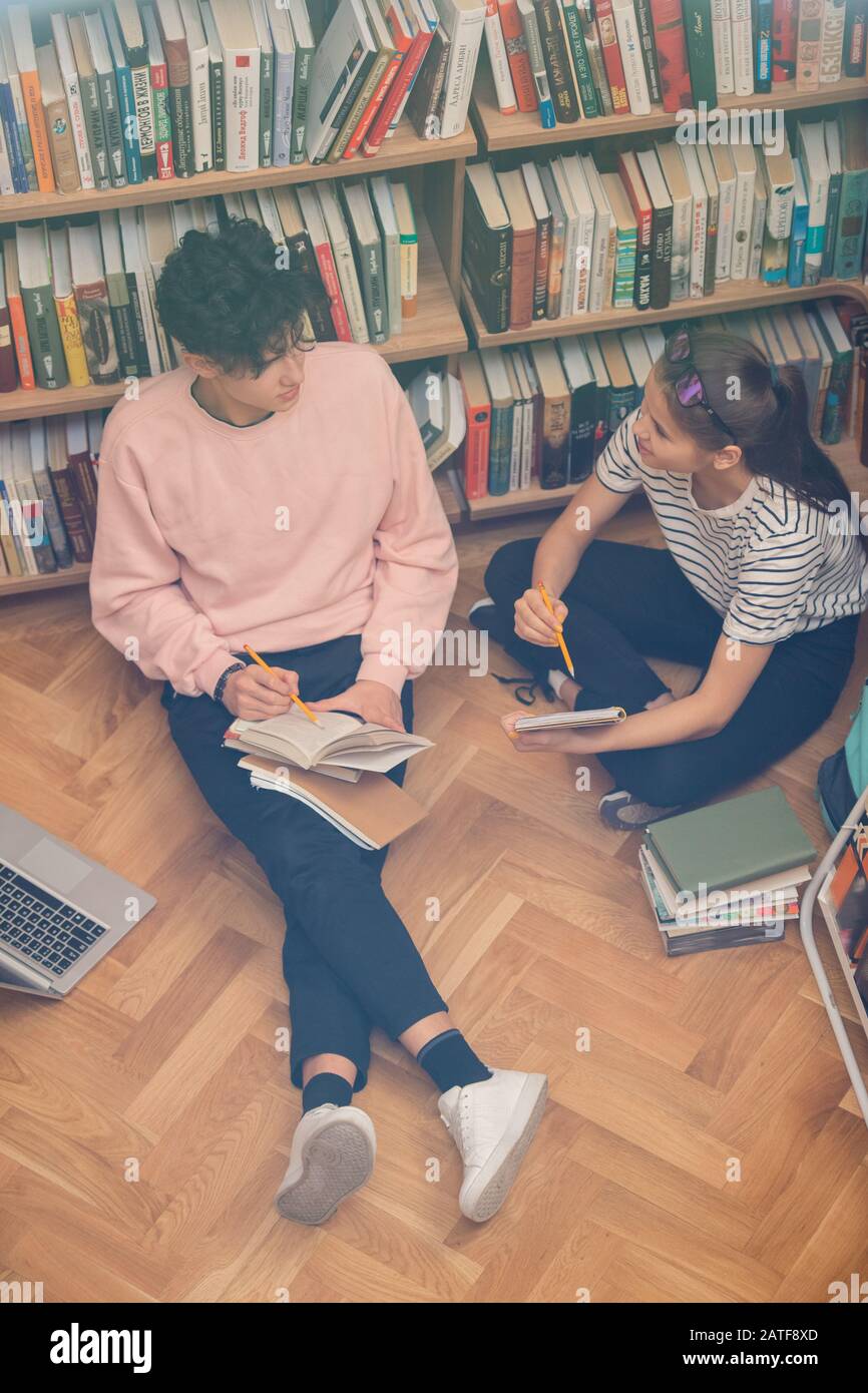Due compagni di classe adolescenti con libri che discutono di passaggio da romanzo o storia Foto Stock