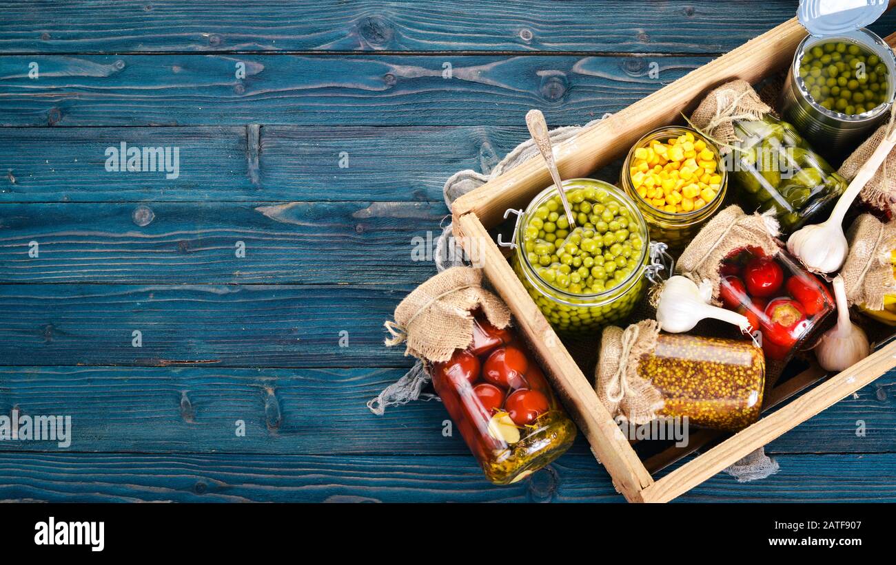 Alimenti decapati in lattine. Scorte di cibo. Vista dall'alto. Su uno sfondo di legno. Spazio di copia. Foto Stock