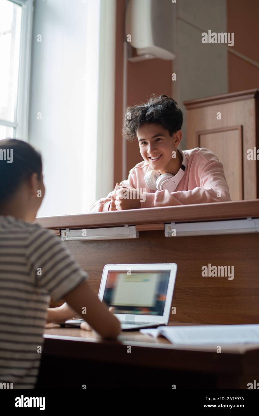 Allegro bel ragazzo in casualwear parlare con il suo compagno di classe in biblioteca Foto Stock