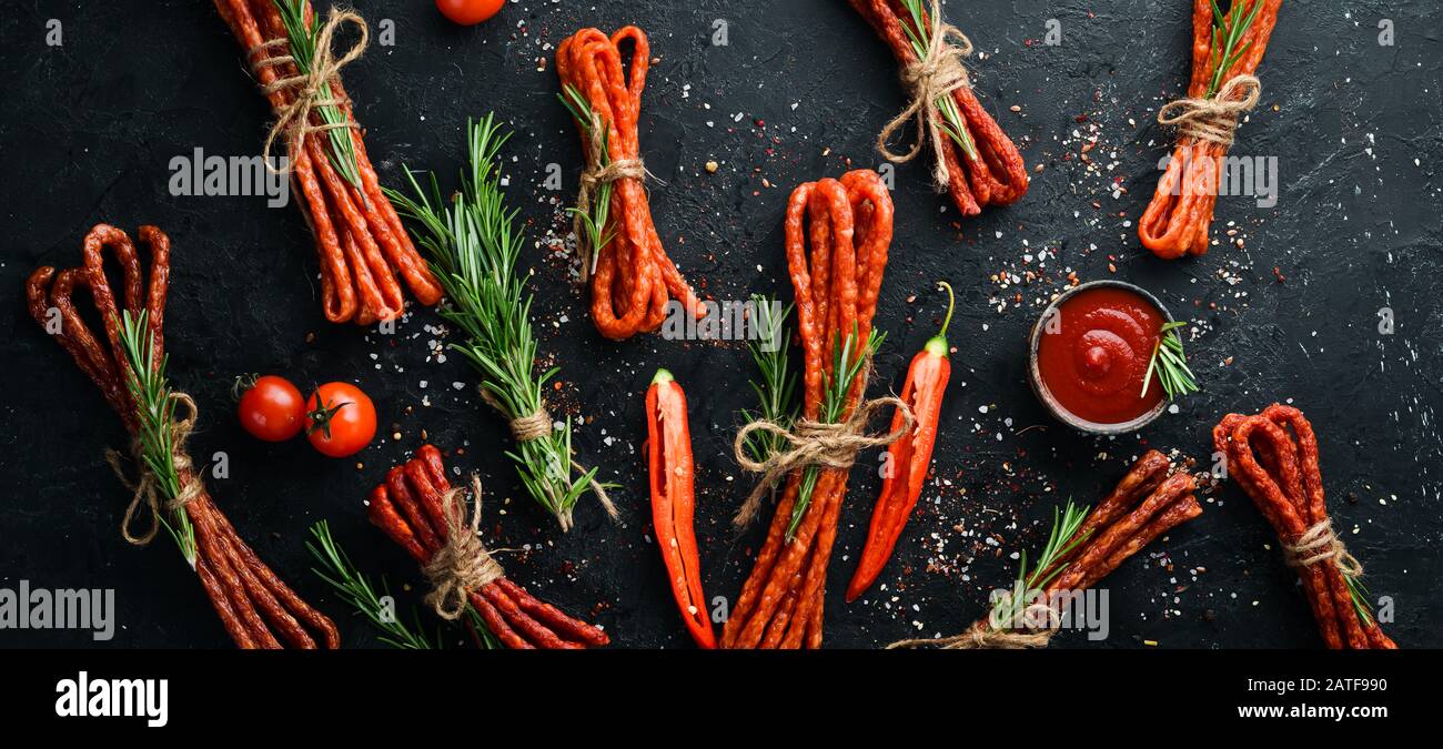 Salsicce secche con peperoncino su fondo di pietra nera. Peperoni cileni, Kabanosy. Vista dall'alto. Spazio libero per il testo. Foto Stock
