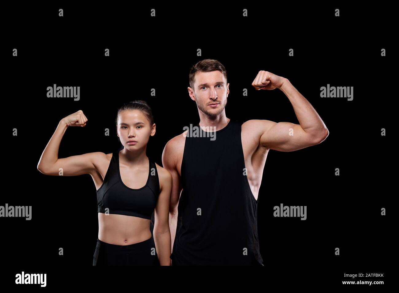 Giovane sportivo muscolare e donna calzata in abbigliamento sportivo che mostra la loro forza Foto Stock