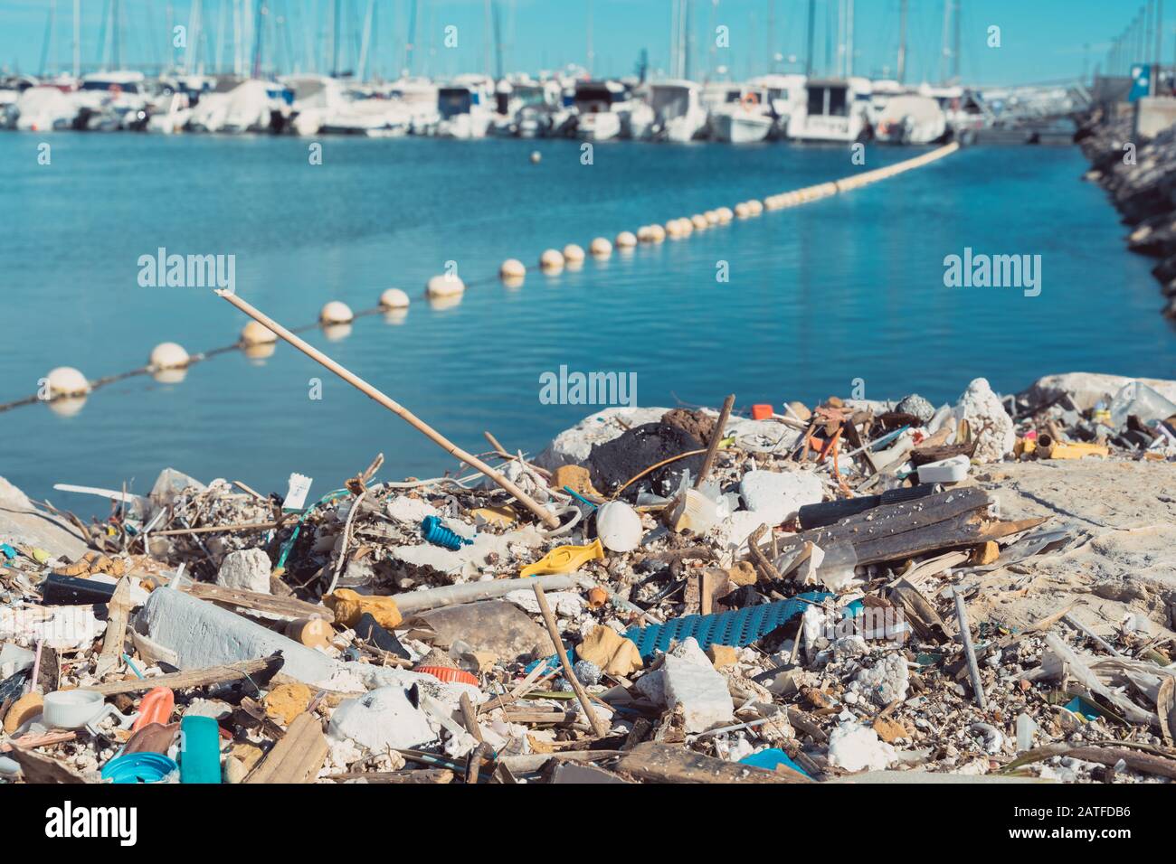 Oggetti in plastica lavati sulla riva e yacht sullo sfondo.inquinamento marino. Foto Stock