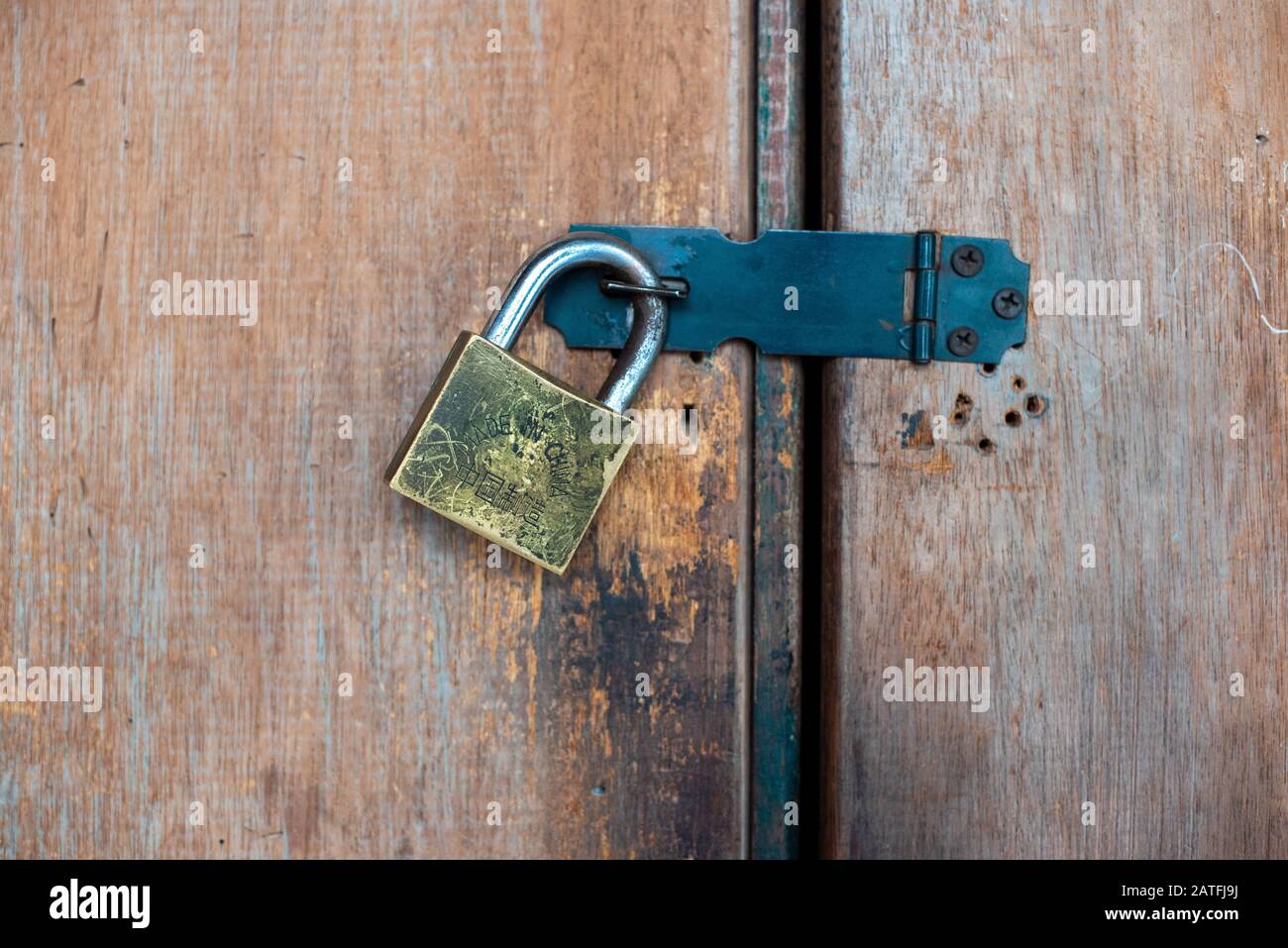Primo piano fotografia di un classico lucchetto di sicurezza in acciaio trovato sulla porta di legno di una casa Foto Stock