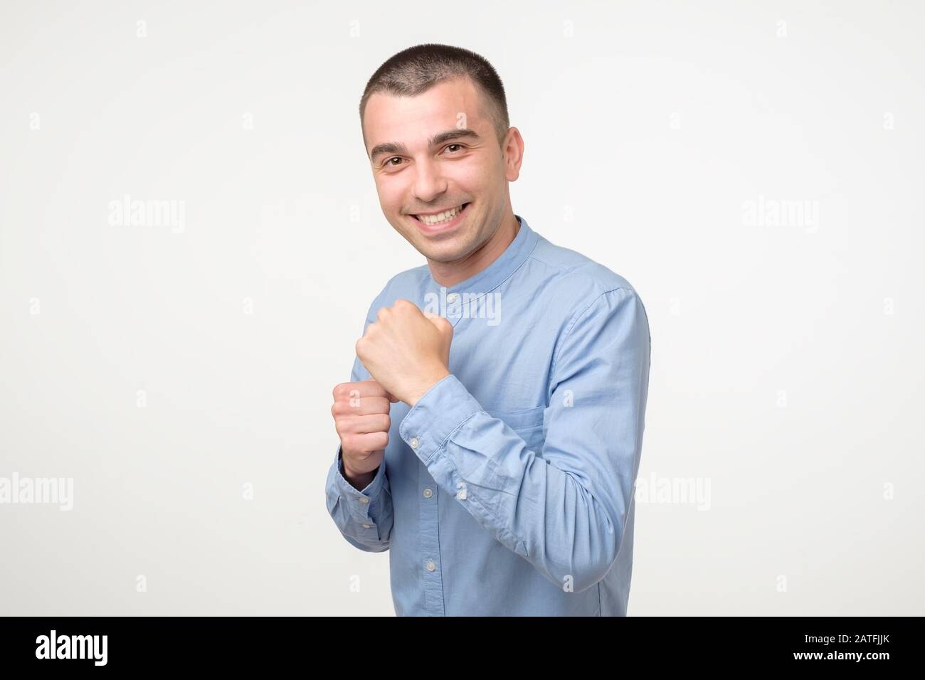 Bel giovane ispanico in posizione di combattimento sorridente e ridente. Emozione umana facciale positiva. Foto Stock