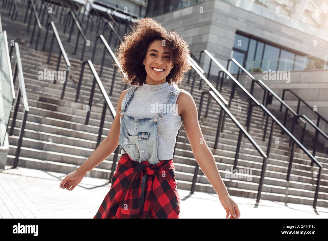 Giovane donna nella strada della città che si erge su scale sorridente allegro Foto Stock