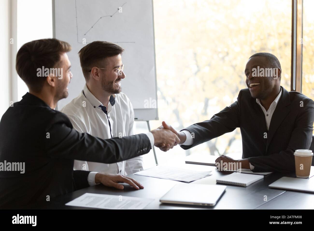 L’uomo d’affari africano felice stringe le mani con il partner commerciale europeo Foto Stock