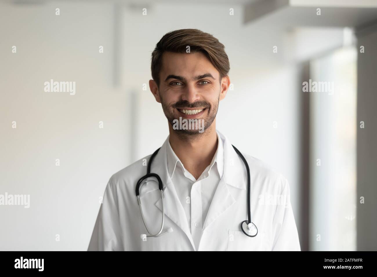 Headshot ritratto medico sorridente indossando uniforme con stetoscopio sul collo Foto Stock