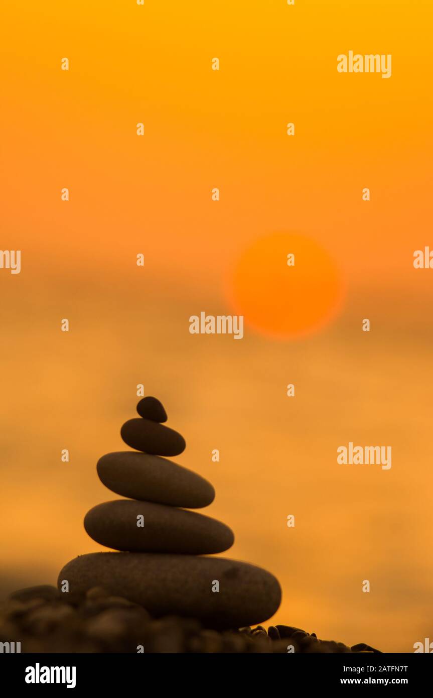 Piramide piegata Zen pietre ghiaia sul mare spiaggia al tramonto Foto Stock