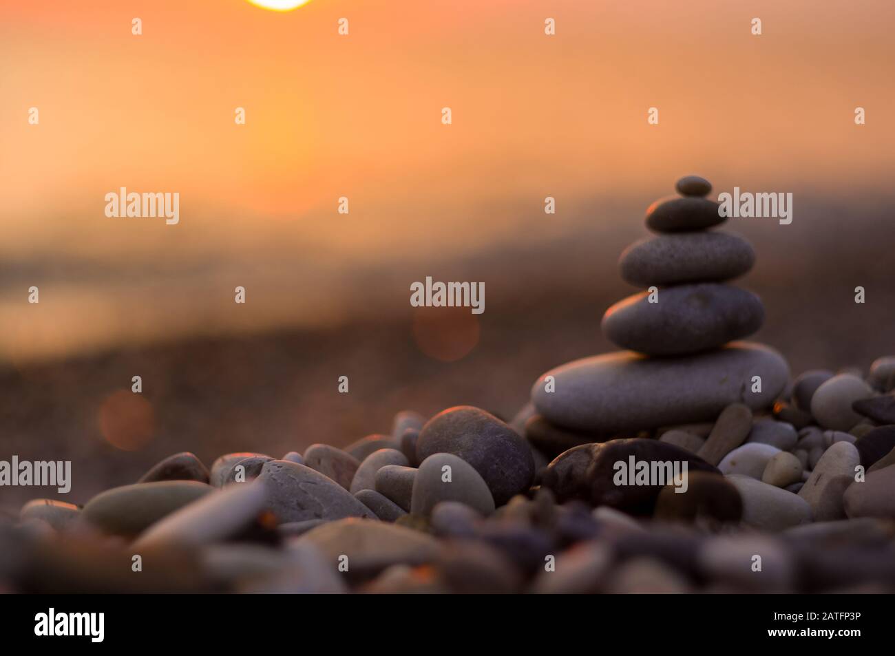 Piramide piegata Zen pietre ghiaia sul mare spiaggia al tramonto Foto Stock