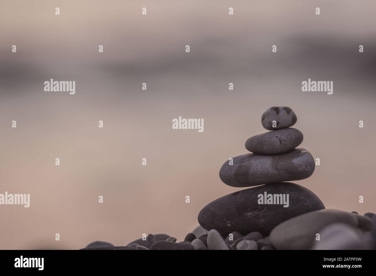 Piramide piegata Zen pietre ghiaia sul mare spiaggia al tramonto Foto Stock