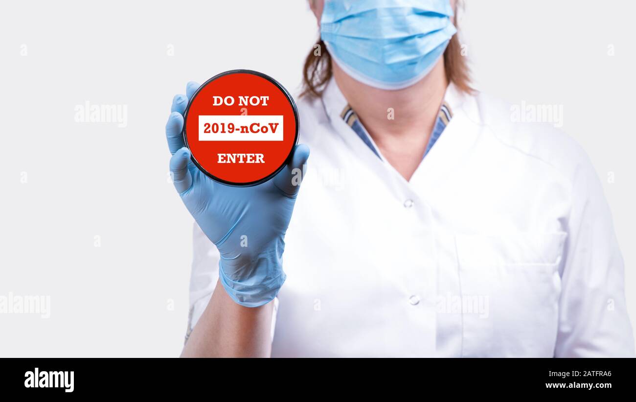 La mano del medico femminile che tiene il segno di arresto con il testo non entra nel coronavirus 2019-nCoV contro l'immagine concettuale di sfondo rosso. Foto Stock