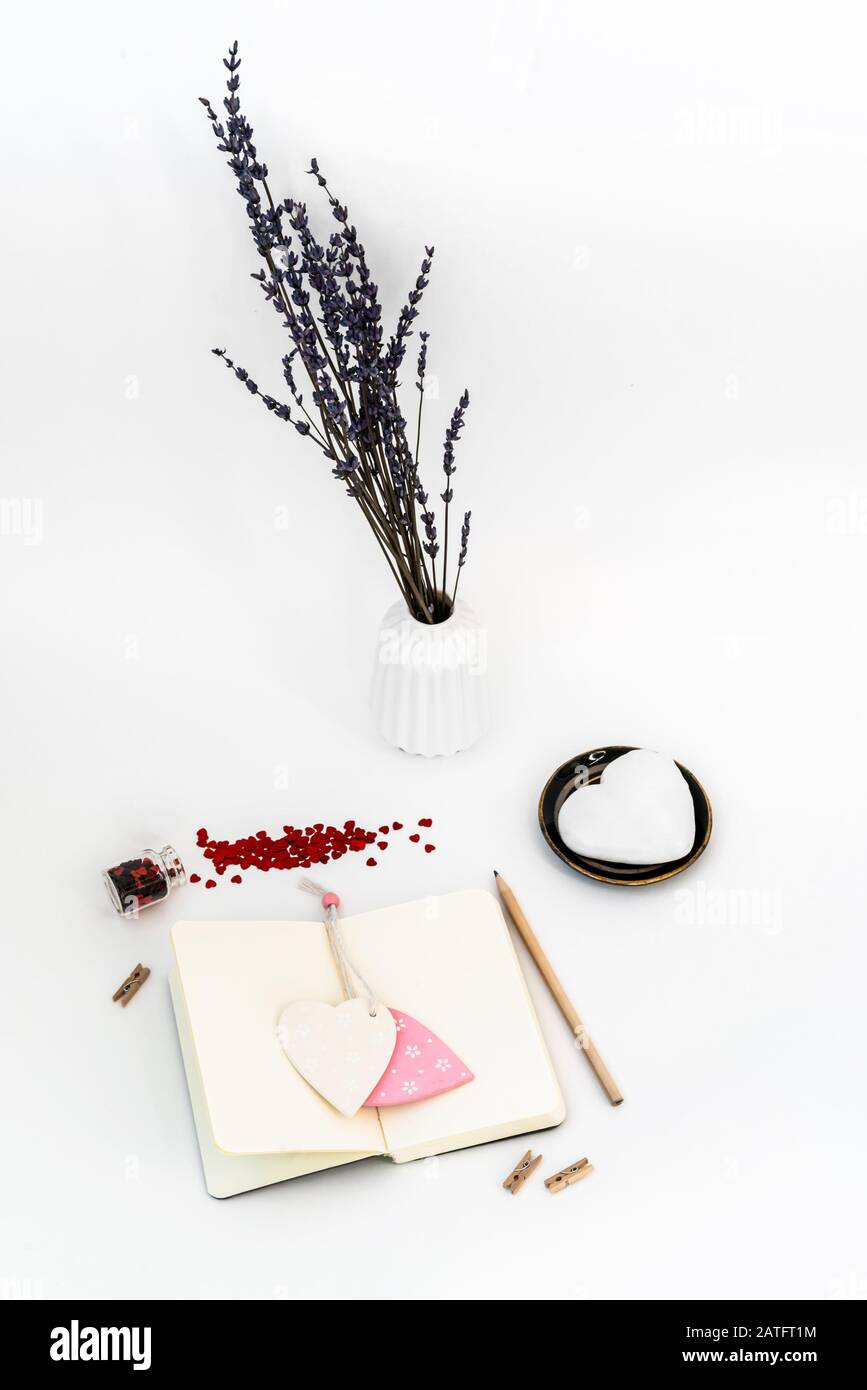 Composizione di San Valentino. Desktop femminile con tazza di caffè e piastra con biscotti allo zenzero a forma di cuore su sfondo bianco. Concetto di festa di San Valentino Foto Stock